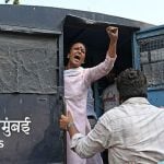A woman in a police van gestures to the crowd by putting her fist in the air