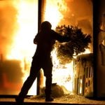 A hooded protester vandalizes the Justice Ministry during clashes in Tirana, Albania, Wednesday, Oct. 14, 2026, as students